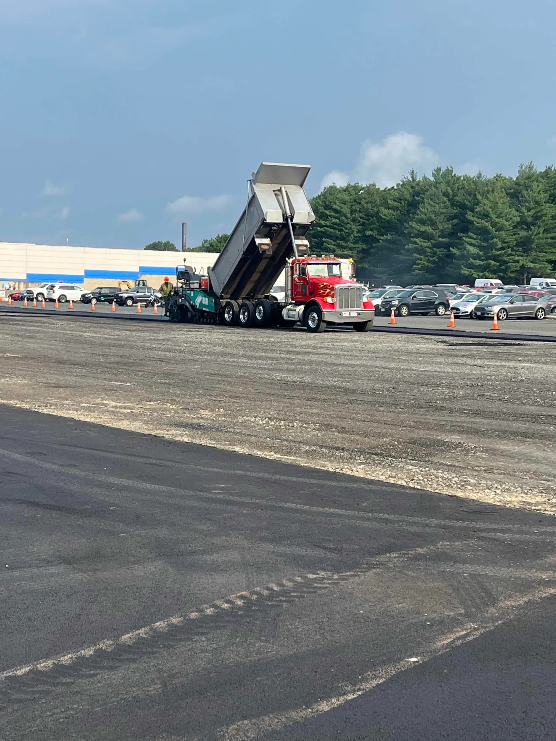 Red dump truck unloading gravel at site.