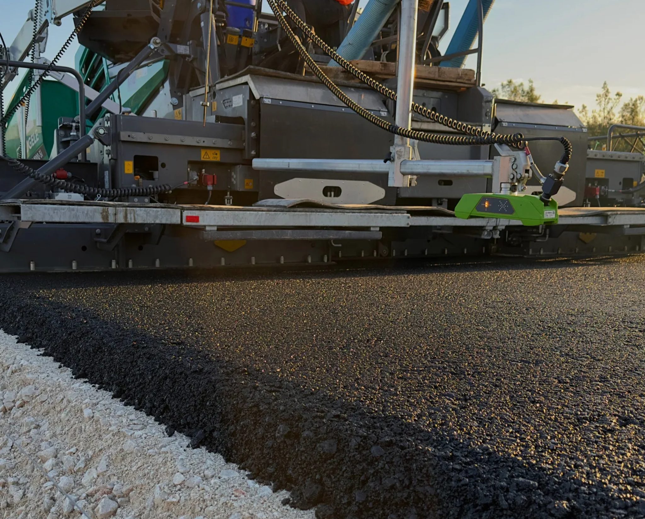 Machine paving fresh asphalt on a road.
