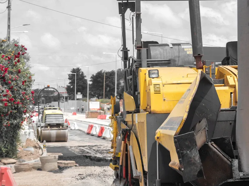 Asphalt paver and road roller working together on new pavement