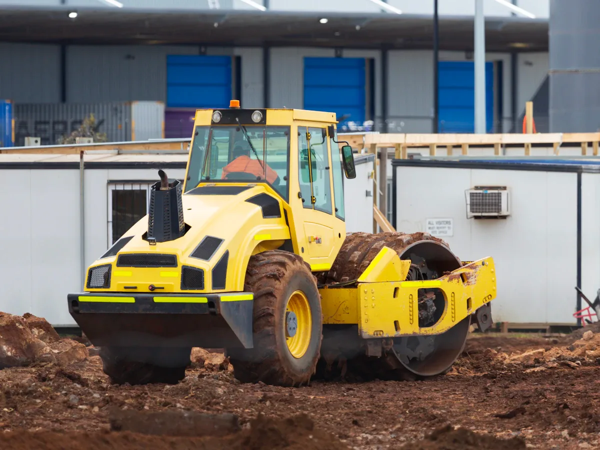 Compactor and excavator working on a road construction site
