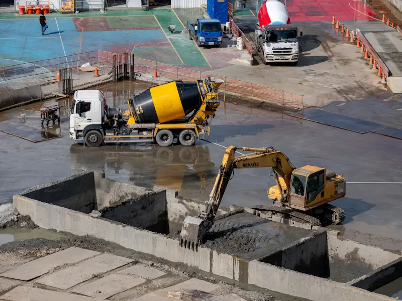 Concrete mixer truck and excavator on a site development project Concrete mixer truck and excavator on a site development project