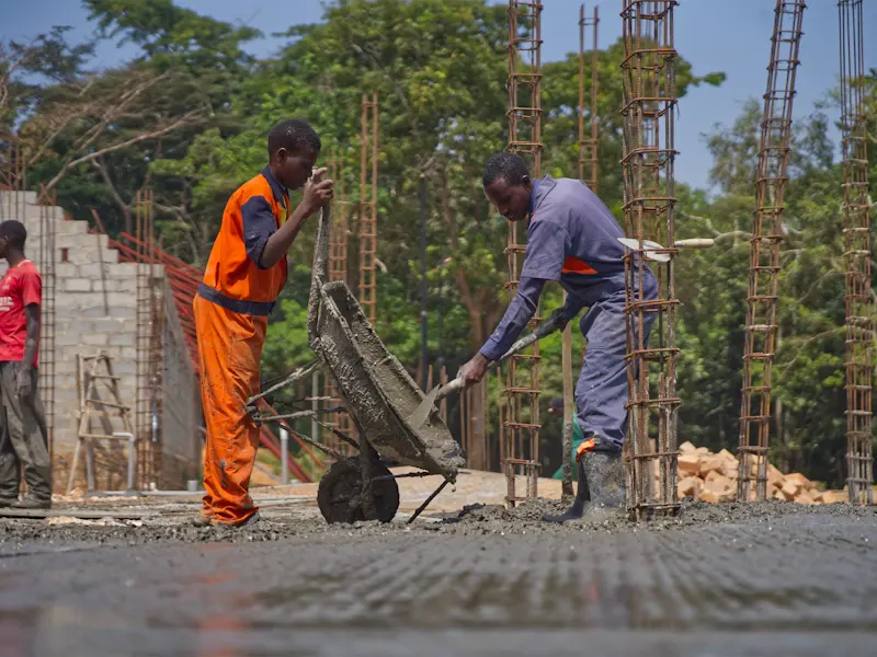 Crew pouring and spreading fresh concrete from a wheelbarrow