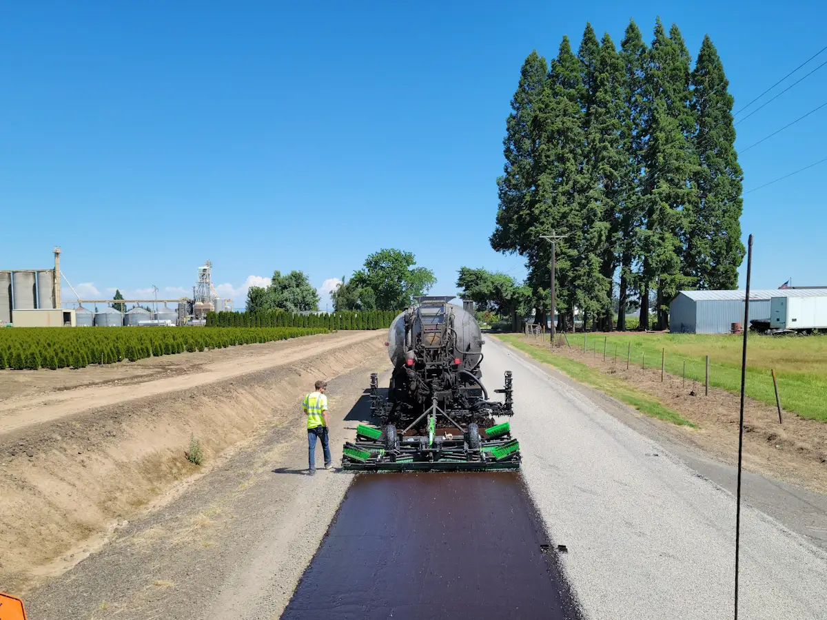 Crew sealing an asphalt road surface with commercial equipment