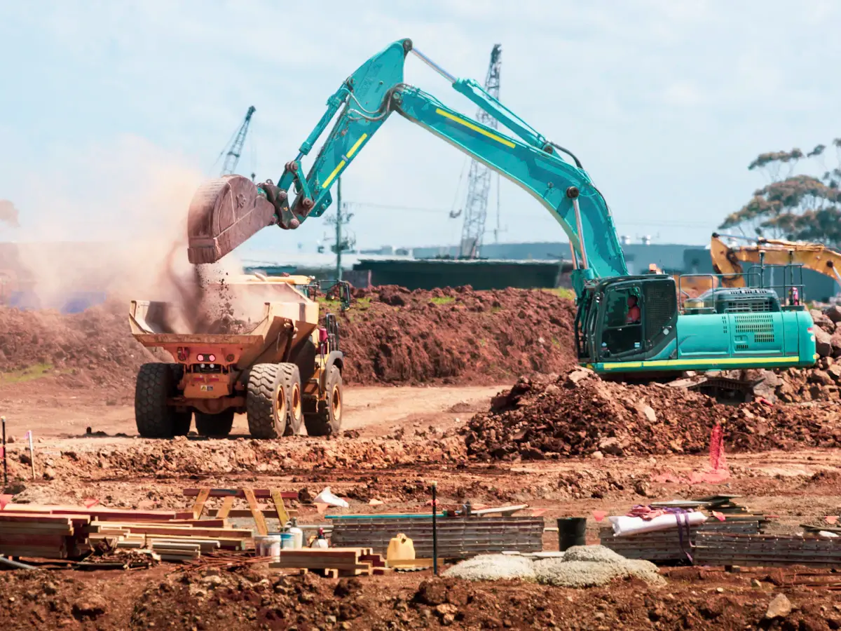 Excavator loading soil into a dump truck during site excavation