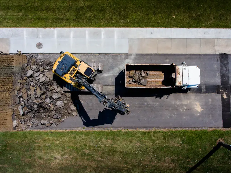 Heavy equipment and dump truck removing old asphalt for site development