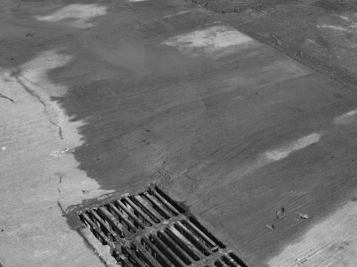 Metal drainage grate set into concrete pavement to move stormwater