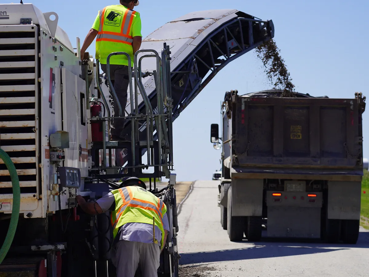 Milling machine removing old pavement and loading it into a truck