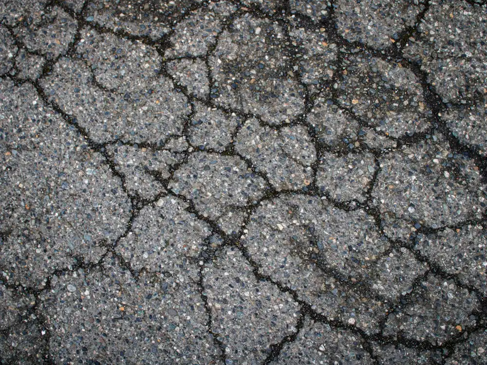Web of cracks spreading across worn asphalt pavement that needs an overlay